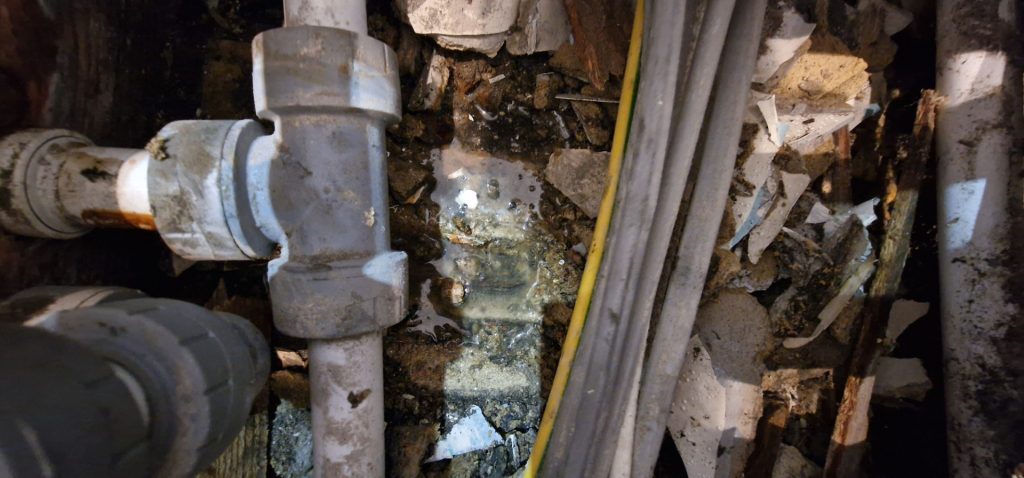 Bathroom pipe leak causing water damage behind wall during leak investigation in London