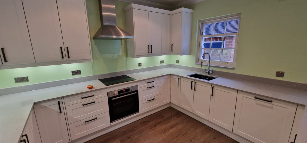 Modern fitted kitchen installation with white cabinets, worktops and integrated appliances in London