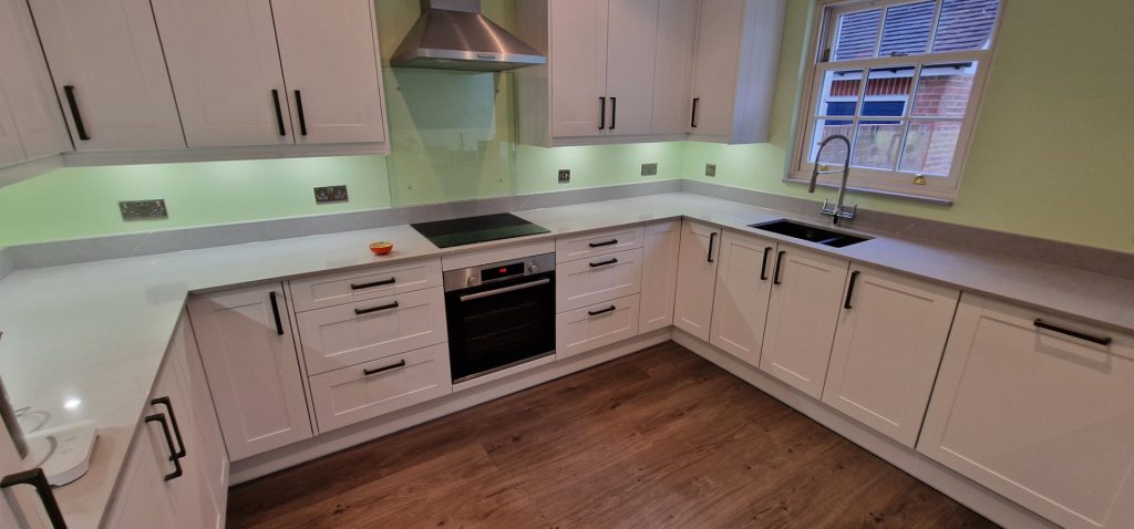 Modern kitchen installation with white cabinets worktops and integrated appliances